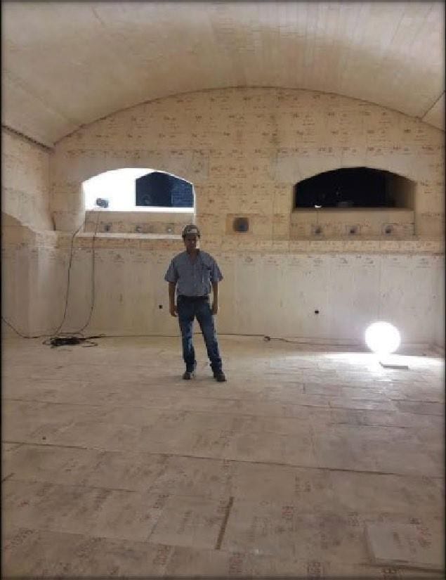 Persona de pie dentro del arco refractario de un horno de vidrio, como referencia de escala